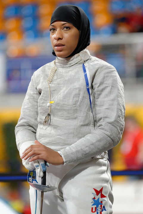 Ibtihaj Muhammad in fencing attire and holding a foil at the Olympics. She is wearing a hijab. 