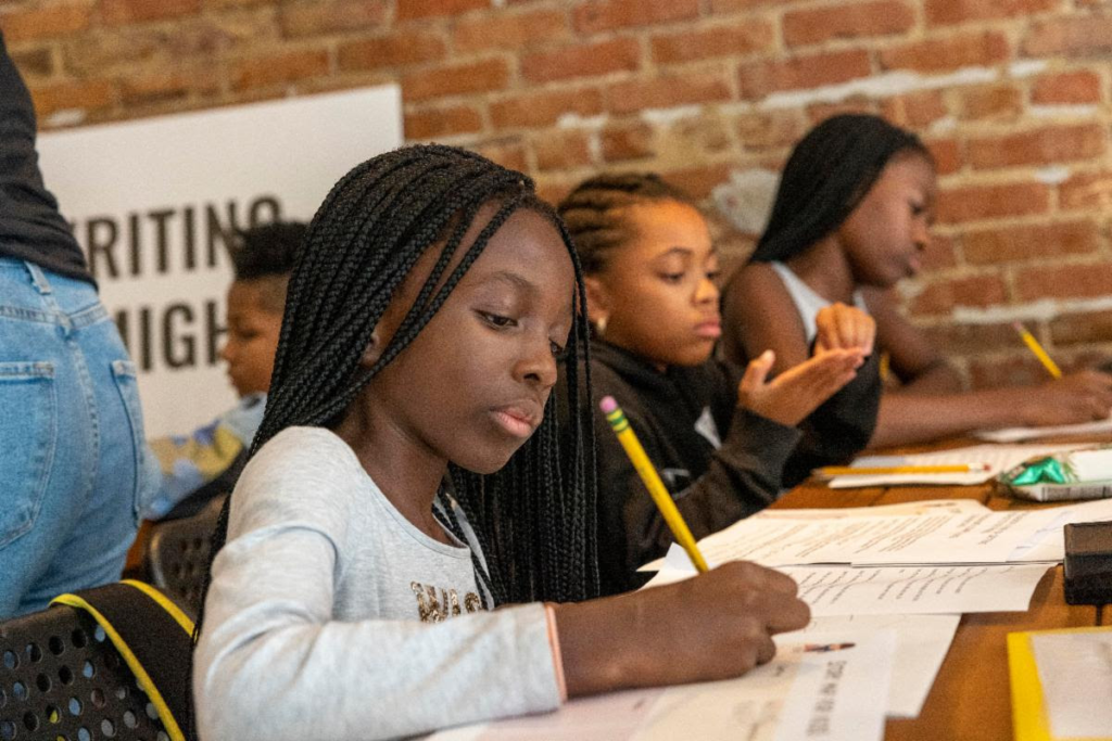 African American children focusing on writing at the Mighty Writers workshop