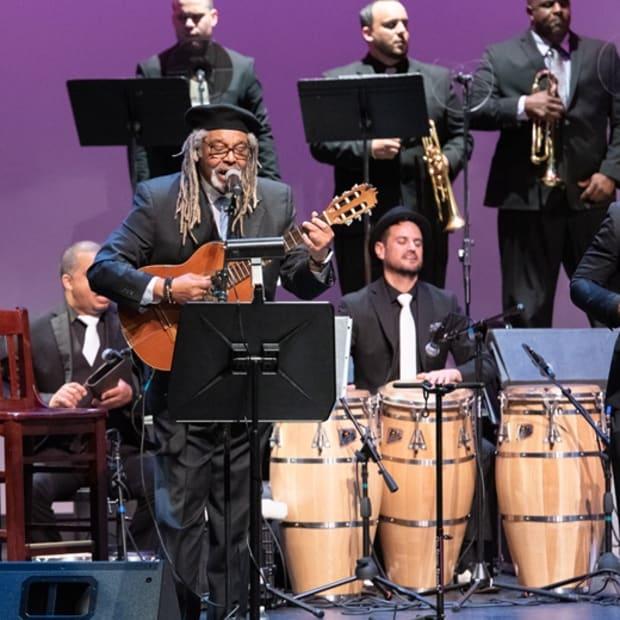 Afro Cuban All Stars with singer playing guitar, congo drummer, trumpet players, and other instrumentalists