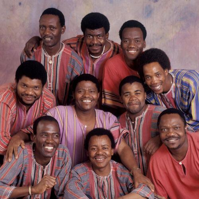 Ladysmith Black Mambazo, consisting of 10 members, posing in kaftans for a group shot