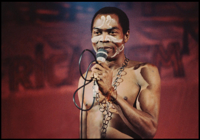 Fela Kuti in face and body paint, singing
