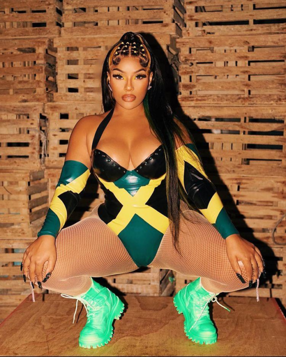 Stefflon Don, in a leotard with a Jamaican flag motif, fishnet tights, and bright green combat boots