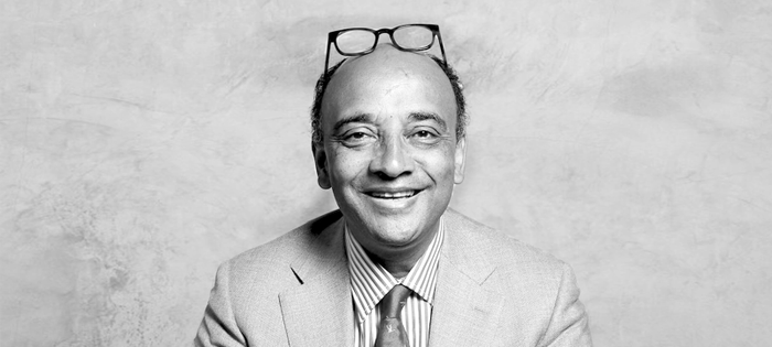 Black and white photograph of Kwame Anthony Appiah, glasses on top of his head and smiling