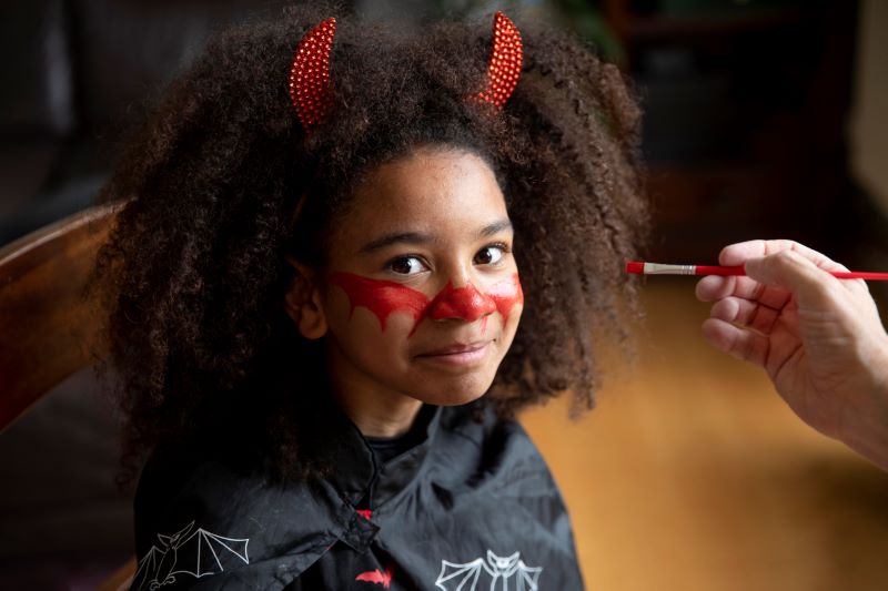 African American girl wearing devil horn headbands with her face painted