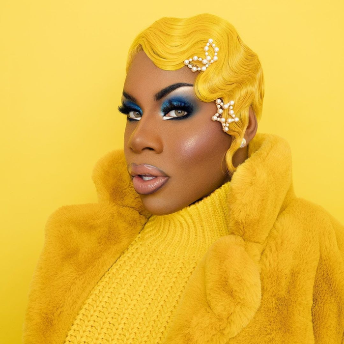 MonetXChange in wavy short wig with pearl clips, fur jacket, and knit sweater