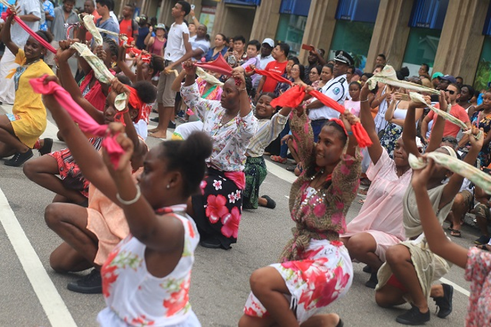 Dancers holding scarves and kneeled in the middle of a parade performance