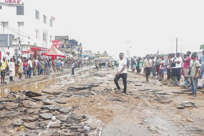 A man wading through a flooded street in Ghana with many onlookers