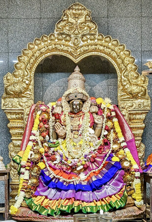 An ornate statue of Sri-Lakshmi, covered in stringed flowers and colorful fabrics