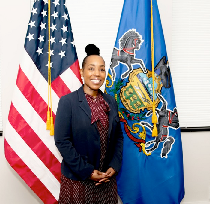 Dr. Nikia Owens standing in front of the U.S. flag 