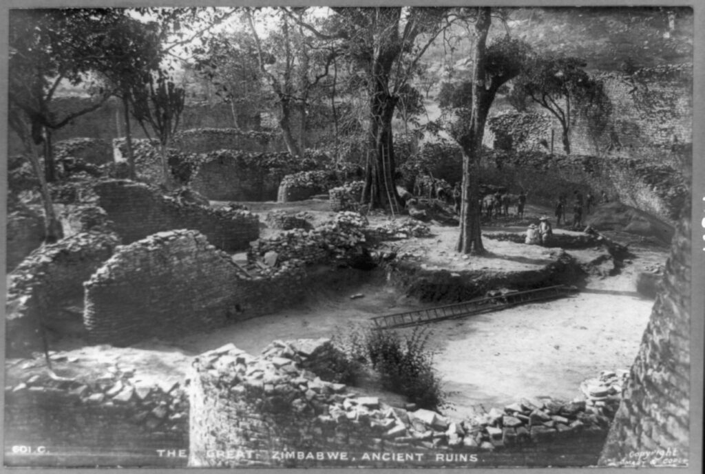 A black and white photograph of Great Zimbabwe, with multiple remains of stone walls and trees