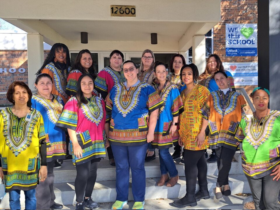 Group of elementary school teachers, some Black and most white, wearing dashiki