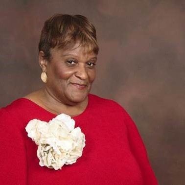 Photo of Rev Dr. Marsha Brown Woodard in red top with large white flowers