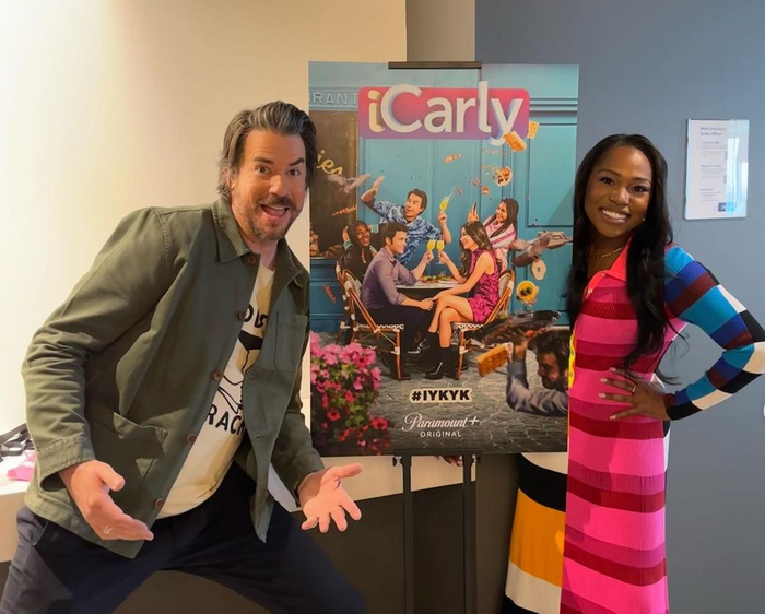 Laci Mosley in front of the iCarly promotional poster, with co-star Jerry Trainor 