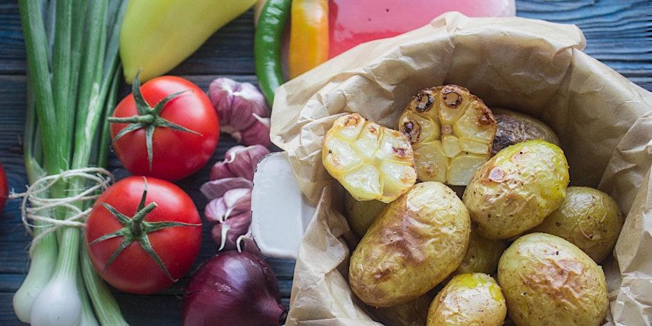 An array of vegetables including green onions, tomatoes, garlic, onion, and potatoes