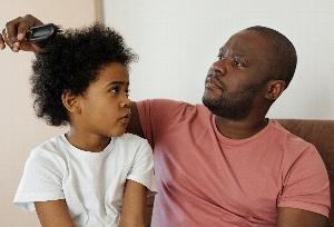 Black father combing young daughter's hair