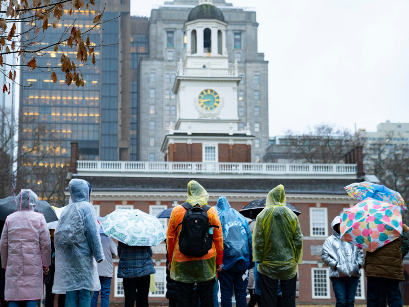 rainy day outside Independence Hall with tourists gathered outside in ponchos and holding umbrellas