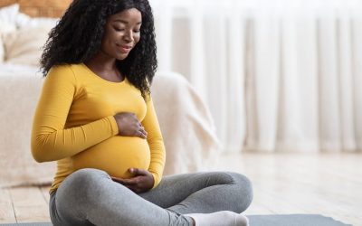 expectant mother holding belly while sitting on floor