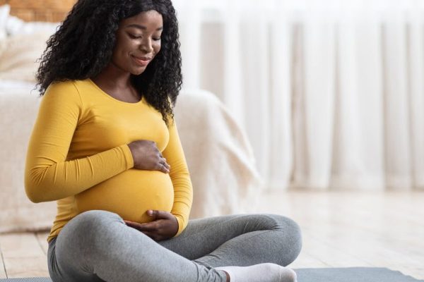expectant mother holding belly while sitting on floor