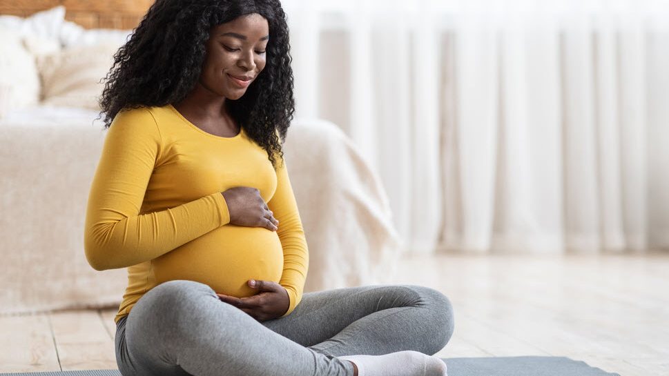 expectant mother holding belly while sitting on floor