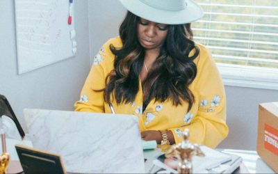 Black woman wearing a cowboy hat browsing the computer in her office
