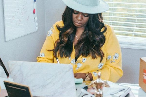 Black woman wearing a cowboy hat browsing the computer in her office