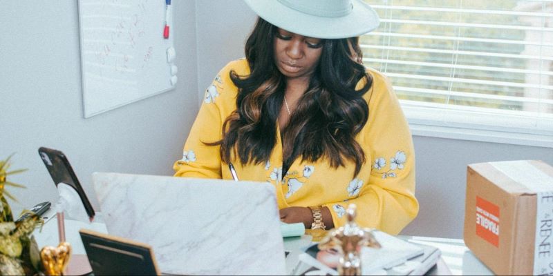 Black woman wearing a cowboy hat browsing the computer in her office