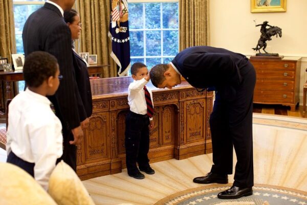 Boy feeling Barack Obama's hair as he leans down and lets him touch it