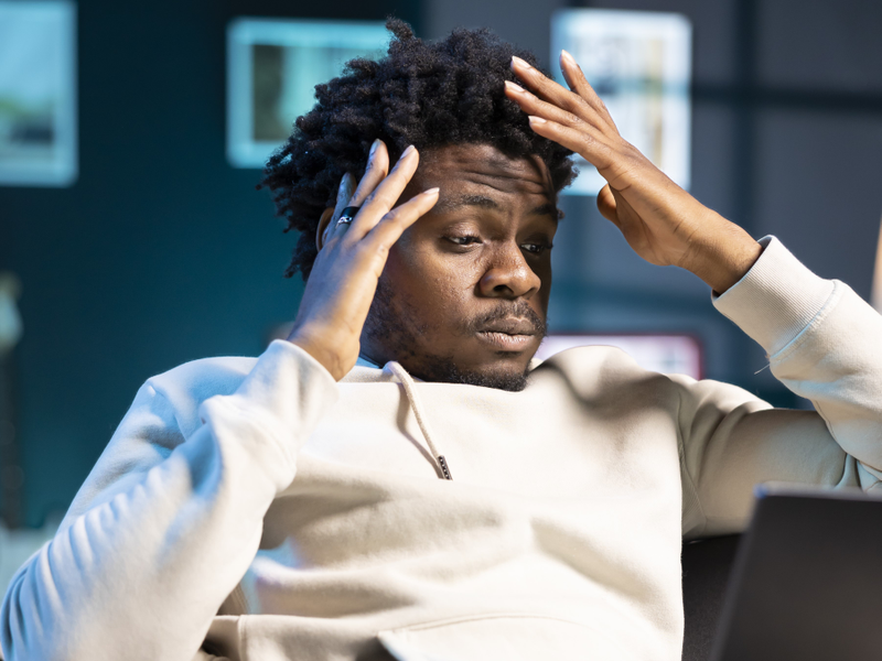 Overwhelmed African American man with hands to his head