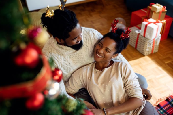 African American couple relaxing in living room with Christmas tree and gifts