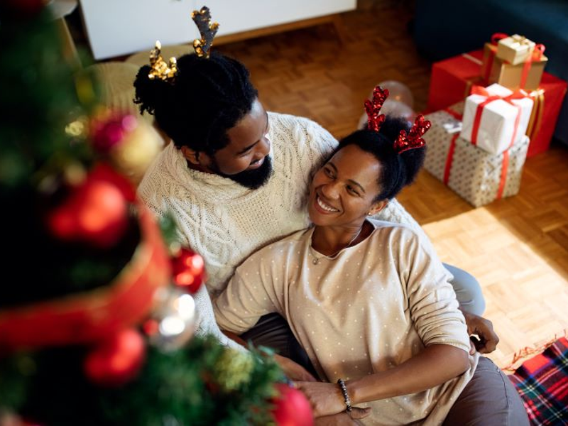 African American couple relaxing in living room with Christmas tree and gifts