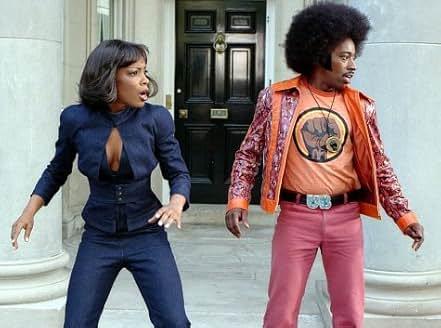 scene from Undercover Brother 1: Aunjanue Ellis-Taylor in form-fitting spy outfit and Eddie Griffin in 1970s style jacket, bright pants, and afro.