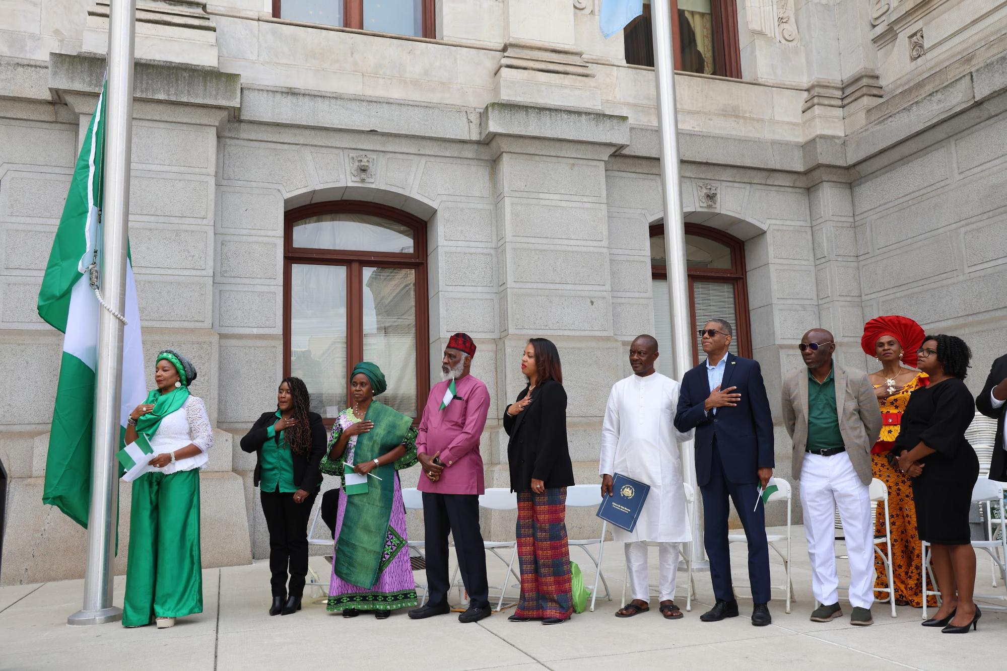 Event hosts and speakers raising the Nigerian flag in front of Philadelphia City Hall