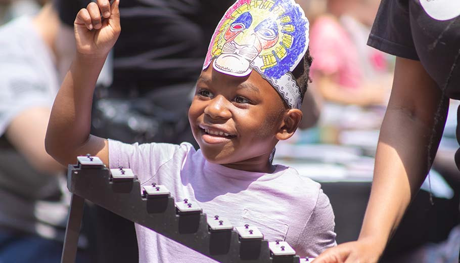 African American boy wearing a handmade paper headband smiling