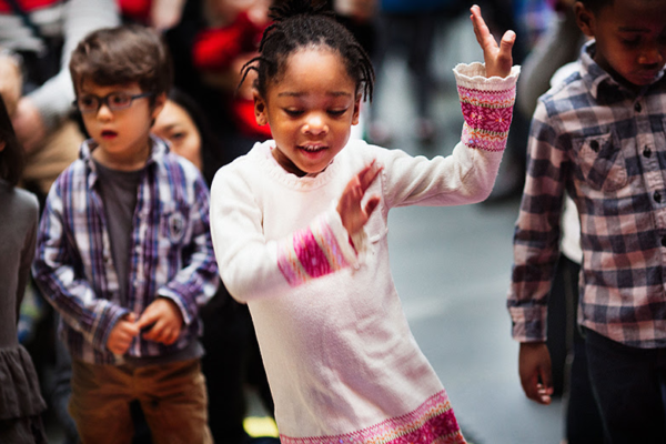 Black girl dancing among group of children