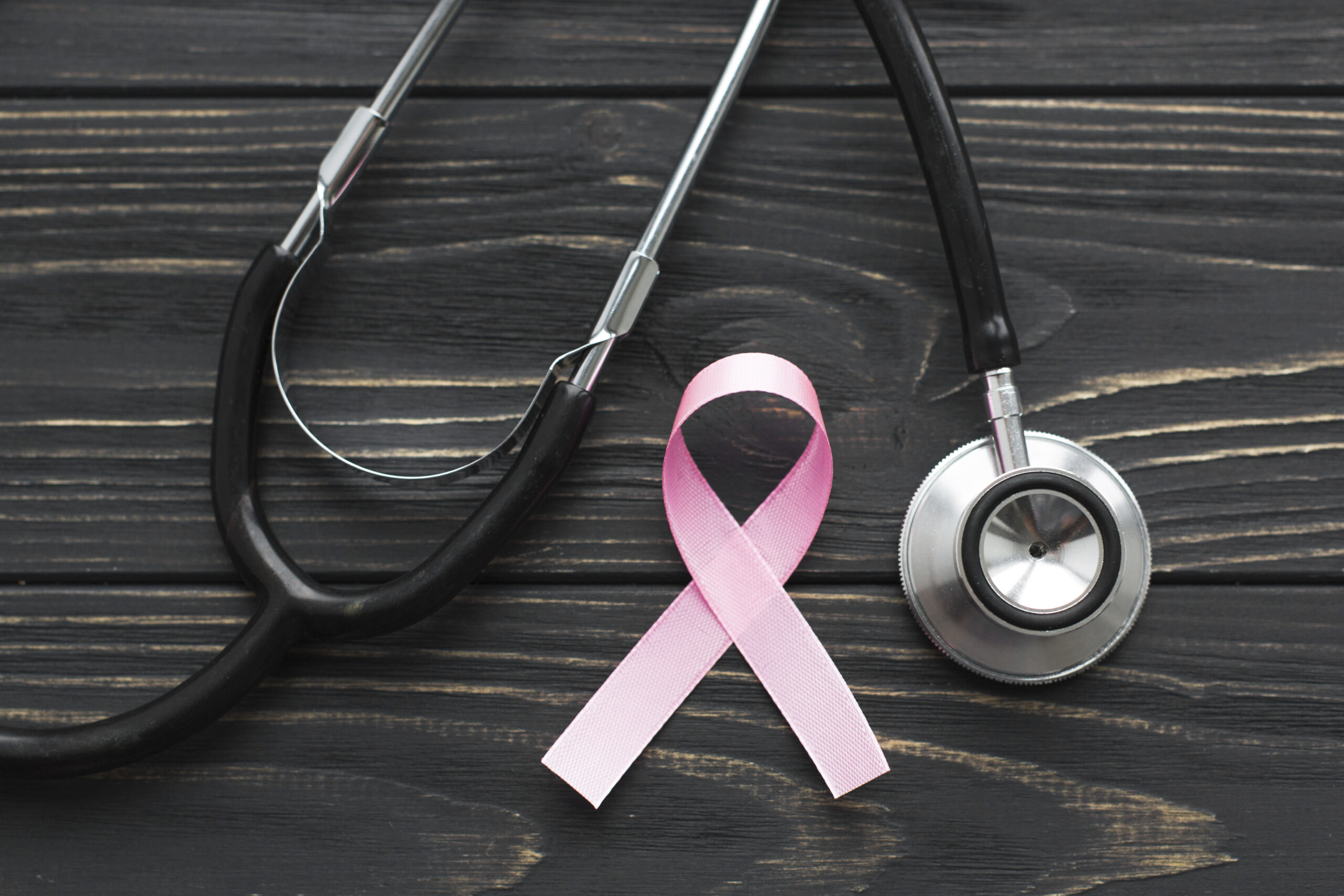 Pink ribbon and stethoscope against a dark background