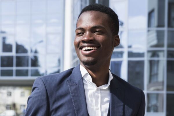 Smiling African American man wearing suit in front of corporate building