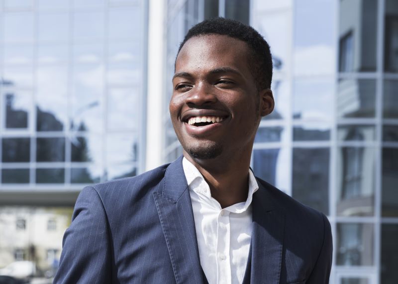 Smiling African American man wearing suit in front of corporate building