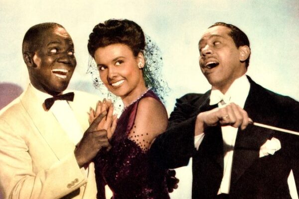 Left to Right: Bill Robinson, Lena Horne, Cab Calloway in the 1943 musical film Stormy Weather. Robinson is in a light colored suit, Horne is wearing a black short veil and halter dress with arm-length gloves, and Calloway is wearing a suit and holding a conductor's baton