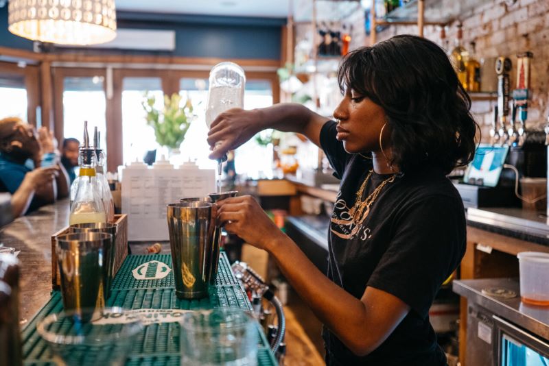 An African American female bartender mixing drinks