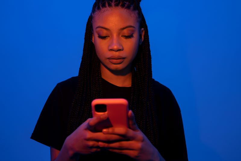 African American woman holding smartphone with serious expression