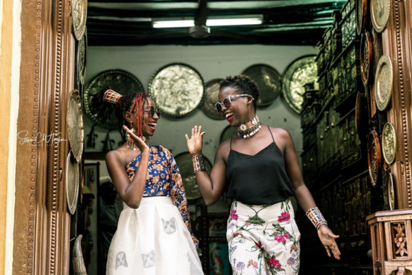 two fashionable Black women high-fiving one another