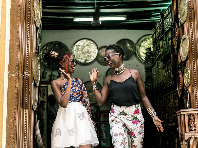 two fashionable Black women high-fiving one another