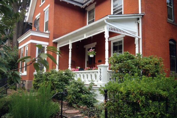 A brick old-fashioned building with a white porch