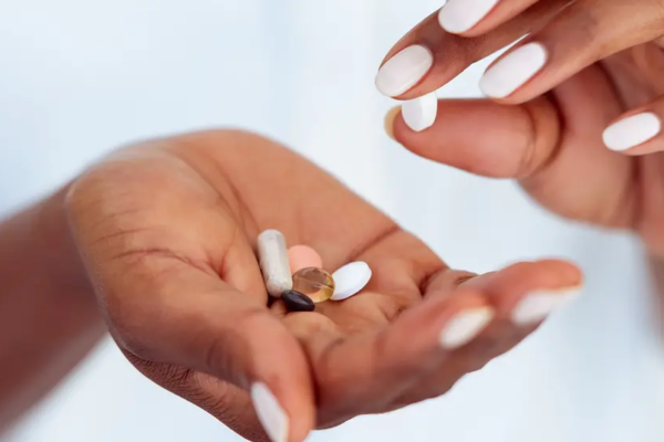 Closeup of Black person's hand picking up vitamins