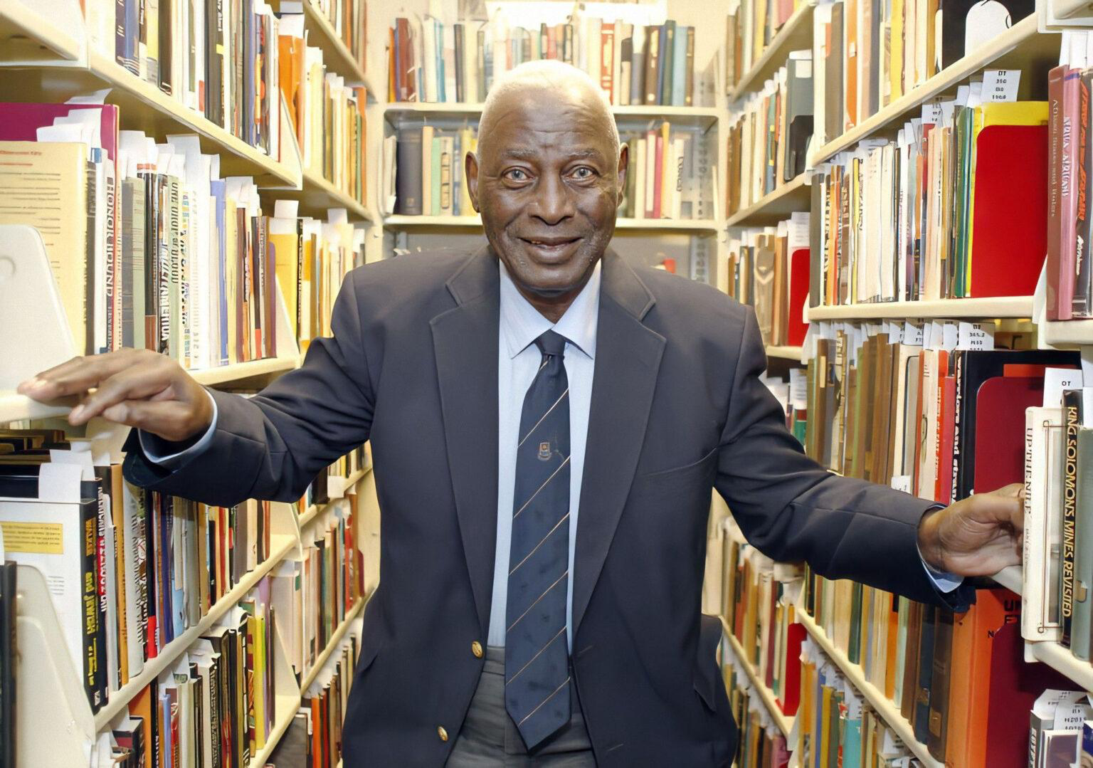 African American historian Charles L. Blockson posing between two library shelves