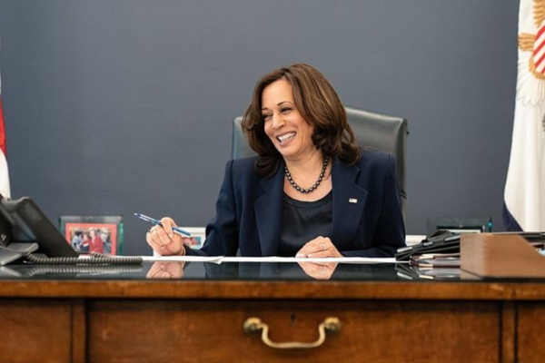 Vice President Kamala Harris sitting at her desk, smiling