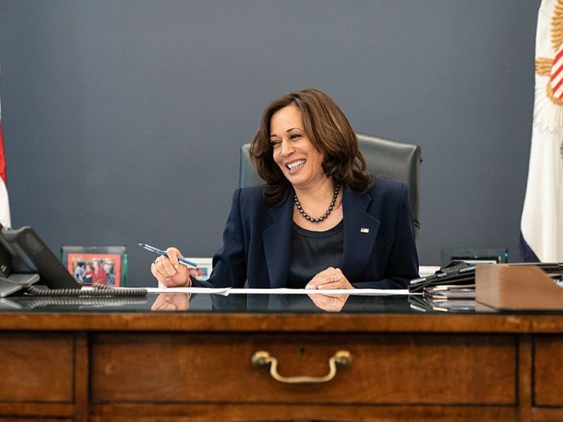 Vice President Kamala Harris sitting at her desk, smiling