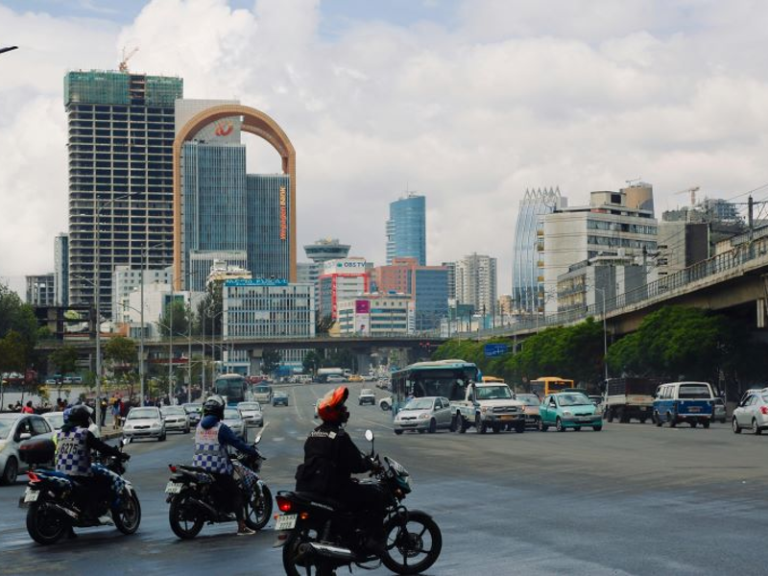 Motorcyclists in the city of Addis Ababa, with tall buildings in the background