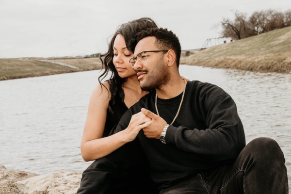 An African American couple huddled together holding hands in front of a lake