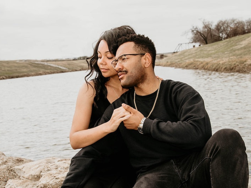 An African American couple huddled together holding hands in front of a lake